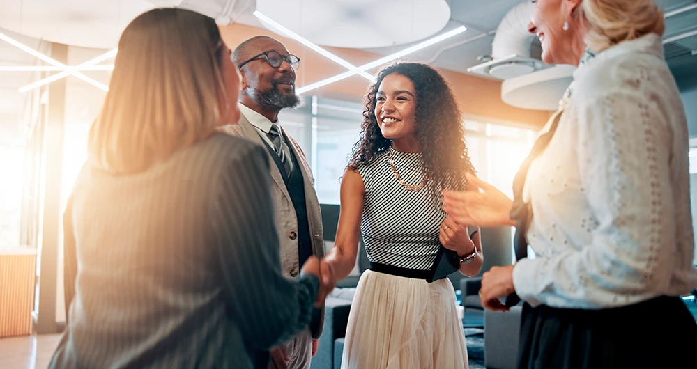 Grupo de pessoas profissionais em ambiente de escritório, sorrindo e conversando durante uma reunião de negócios, promovendo networking de qualidade.